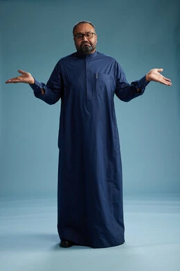 بورتريه لرجل سعودي يقف مرتدياً ثوب كحلي يقوم بايماءات وحركات متنوعه, الوقوف بكامل الجسم, خلفيه زرقاء