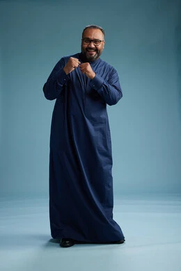 A portrait of a Saudi man standing wearing a navy blue thobe, making various gestures and movements, standing full body, with a blue background.