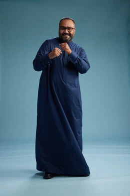 A portrait of a Saudi man standing wearing a navy blue thobe, making various gestures and movements, standing full body, with a blue background.