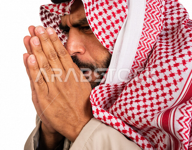 بورتريه لرجل عربي خليجي سعودي يرتدي ملابس الشتاء الدافئة وينفخ بيده، الشعور بالصقيع، ارتداء جاكيت الشتاء، التنفس على اليدين لابقائها دافئة، ايماءات وجه ويدين تدل على البرد الشديد، اجواء شتوية، خلفية بيضاء