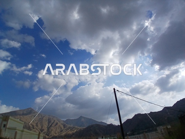 منظر السماء الملبدة بالغيوم في المنطقة الجبلية، المعالم السياحية التاريخية المشهورة، المرتفعات والقمم الجبلية بمنطقة الباحة في قرية ذي العين الأثرية جنوب المملكة العربية السعودية،  البيوت السكنية والطرقات المهيئة في المدينة، الأشجار والنباتات الخضراء