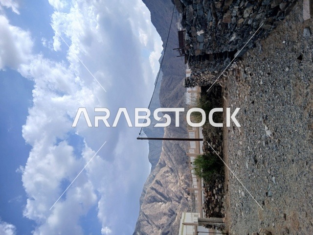 منظر السماء الملبدة بالغيوم في المنطقة الجبلية، المعالم السياحية التاريخية المشهورة، المرتفعات والقمم الجبلية بمنطقة الباحة في قرية ذي العين الأثرية جنوب المملكة العربية السعودية،  البيوت السكنية والطرقات المهيئة في المدينة، الأشجار والنباتات الخضراء