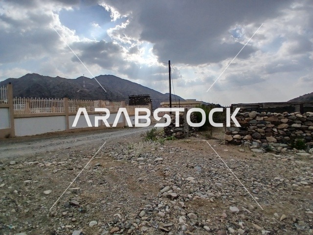منظر السماء الملبدة بالغيوم في المنطقة الجبلية، المعالم السياحية التاريخية المشهورة، المرتفعات والقمم الجبلية بمنطقة الباحة في قرية ذي العين الأثرية جنوب المملكة العربية السعودية،  البيوت السكنية والطرقات المهيئة في المدينة، الأشجار والنباتات الخضراء