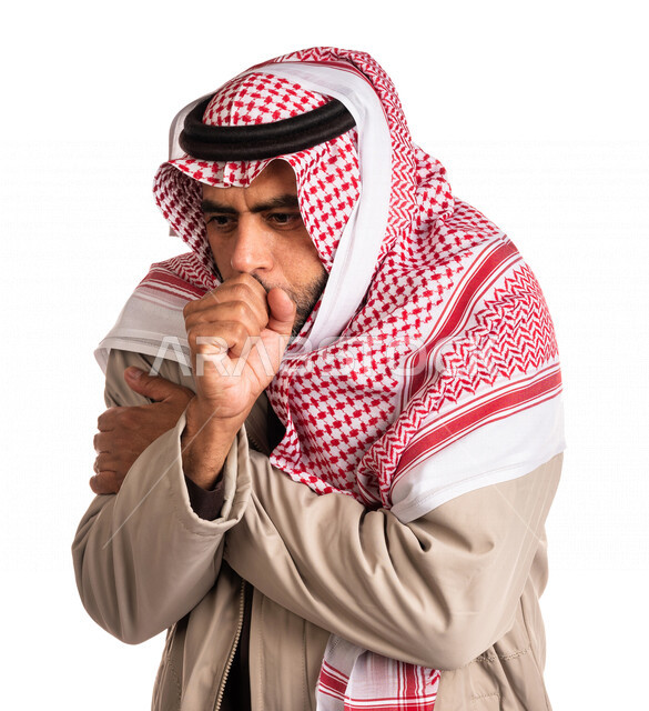بورتريه لرجل عربي خليجي سعودي يرتدي ملابس الشتاء الدافئة وينفخ بيده، الشعور بالصقيع، ارتداء جاكيت الشتاء، التنفس على اليدين لابقائها دافئة، ايماءات وجه ويدين تدل على البرد الشديد، اجواء شتوية، خلفية بيضاء