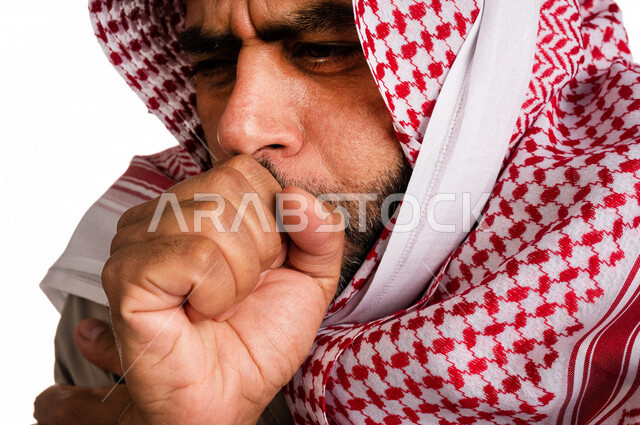 بورتريه لرجل عربي خليجي سعودي يرتدي ملابس الشتاء الدافئة وينفخ بيده، الشعور بالصقيع، ارتداء جاكيت الشتاء، التنفس على اليدين لابقائها دافئة، ايماءات وجه ويدين تدل على البرد الشديد، اجواء شتوية، خلفية بيضاء