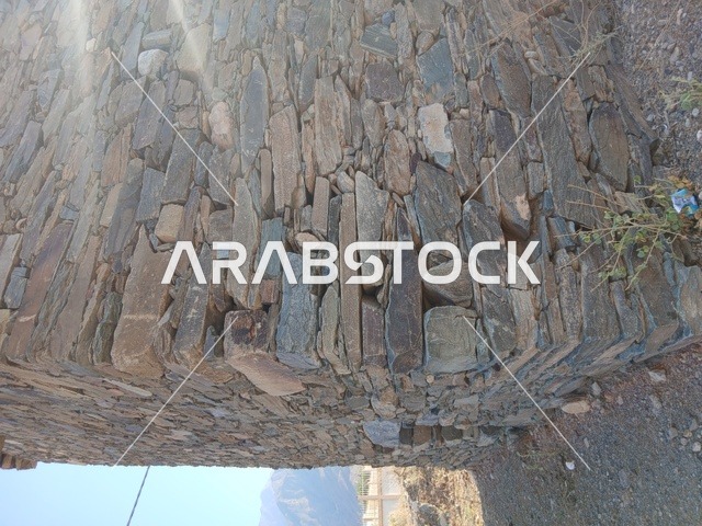 The green plants around the houses and ancient stone buildings in the Al-Hijr area, the famous tourist places and landmarks in the Kingdom of Saudi Arabia, the high mountainous regions, the architectural engineering art in the old style.