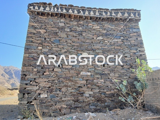The green plants around the houses and ancient stone buildings in the Al-Hijr area, the famous tourist places and landmarks in the Kingdom of Saudi Arabia, the high mountainous regions, the architectural engineering art in the old style.