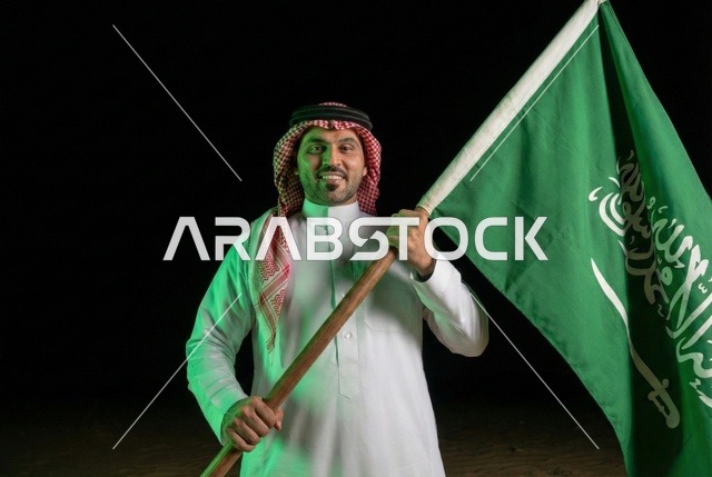 إحياء ذكرى اليوم الوطني السعودي 23 سبتمبر، يوم العلم السعودي 11 مارس, إيماءات الفخر و السرور بالانتماء للوطن, رجل عربي سعودي يرتدي الشماغ والثوب التقليدي يحمل بيده علم المملكة، يوم بدينا 1727 م
