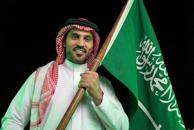 إحياء ذكرى اليوم الوطني السعودي 23 سبتمبر، يوم العلم السعودي 11 مارس, إيماءات الفخر و السرور بالانتماء للوطن, رجل عربي سعودي يرتدي الشماغ والثوب التقليدي يحمل بيده علم المملكة، يوم بدينا 1727 م