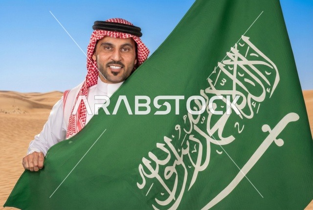 إحياء ذكرى اليوم الوطني السعودي 23 سبتمبر، يوم العلم السعودي 11 مارس, إيماءات الفخر و السرور بالانتماء للوطن, رجل عربي سعودي يرتدي الشماغ والثوب التقليدي يحمل بيده علم المملكة، يوم بدينا 1727 م