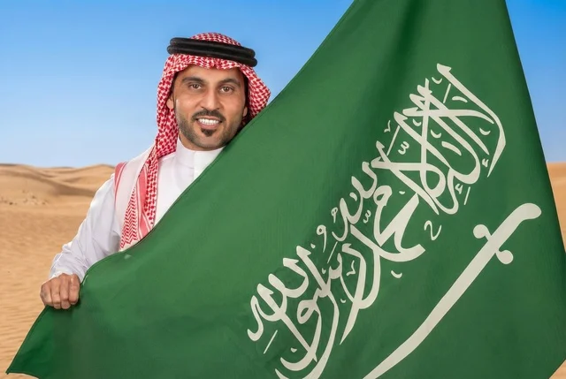 إحياء ذكرى اليوم الوطني السعودي 23 سبتمبر، يوم العلم السعودي 11 مارس, إيماءات الفخر و السرور بالانتماء للوطن, رجل عربي سعودي يرتدي الشماغ والثوب التقليدي يحمل بيده علم المملكة، يوم بدينا 1727 م