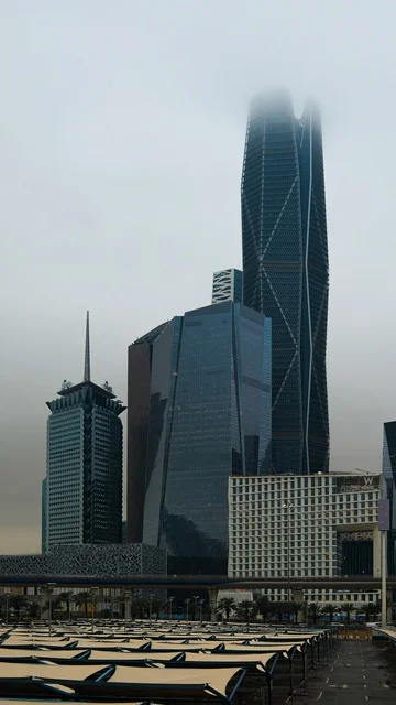 King Abdullah Financial District (KAFD) in Riyadh, the architectural facilities in the Kingdom, the foggy and cloudy atmosphere, distinctive arts and architectural designs for economic buildings and skyscrapers, leading upscale companies in banking and financial technology.