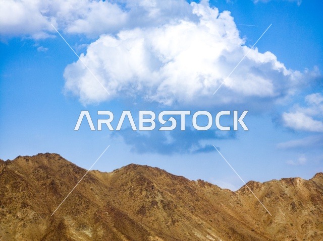 منظر السماء المبلدة بالغيوم فوق جبال مدينة حتا السياحية بإمارة دبي بدولة الإمارات العربية المتحدة ، المرتفعات الجبلية ، خلفية الطبيعة الجبلية ، السياحة في الإمارات ، جبال حتا