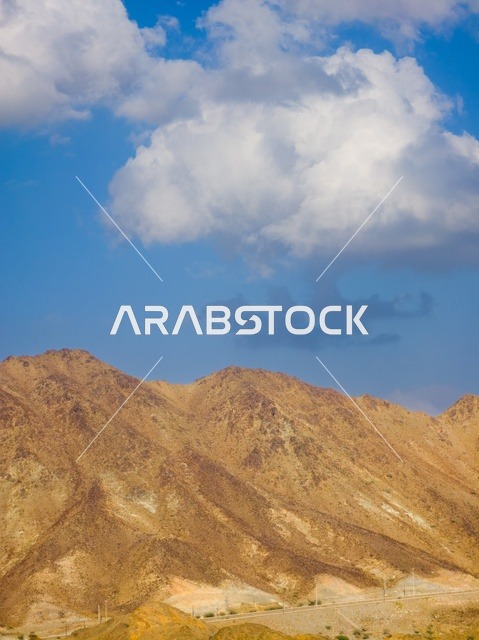 منظر السماء المبلدة بالغيوم فوق جبال مدينة حتا السياحية بإمارة دبي بدولة الإمارات العربية المتحدة ، المرتفعات الجبلية ، خلفية الطبيعة الجبلية ، السياحة في الإمارات ، جبال حتا