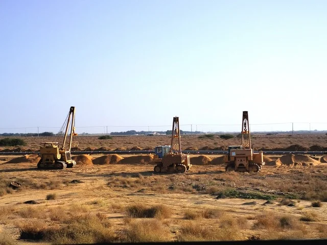 معدات حفر وآليات ثقيلة تعمل في موقع صحراوي، تنفيذ أعمال بنية تحتية وتمهيد أراضٍ، تجهيز مشاريع إنشائية وتنموية، مشهد يعكس التطوير العمراني والصناعي، بيئة عمل مفتوحة في المناطق الصحراوية بالمملكة العربية السعودية