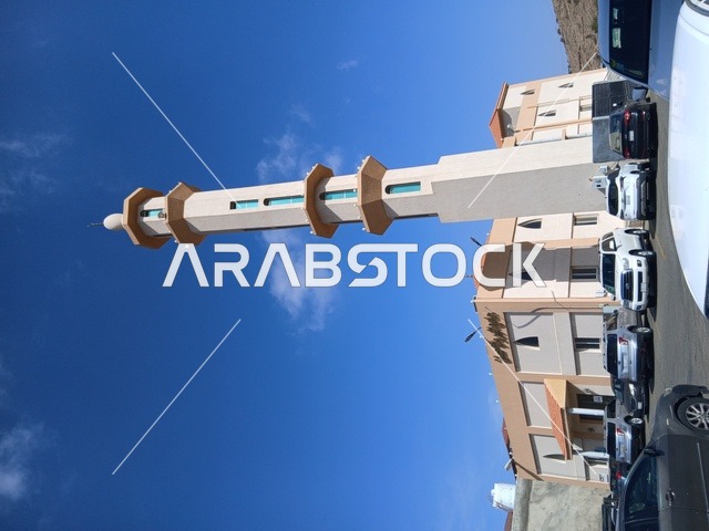 A minaret of a mosque in the Al-Baha region in the archaeological village of Dhai Ain, south of the Kingdom of Saudi Arabia, famous historical tourist landmarks, parking lots around the mosque.