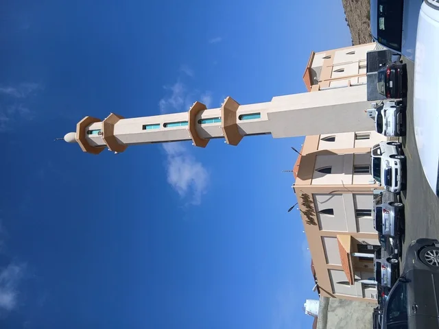 A minaret of a mosque in the Al-Baha region in the archaeological village of Dhai Ain, south of the Kingdom of Saudi Arabia, famous historical tourist landmarks, parking lots around the mosque.