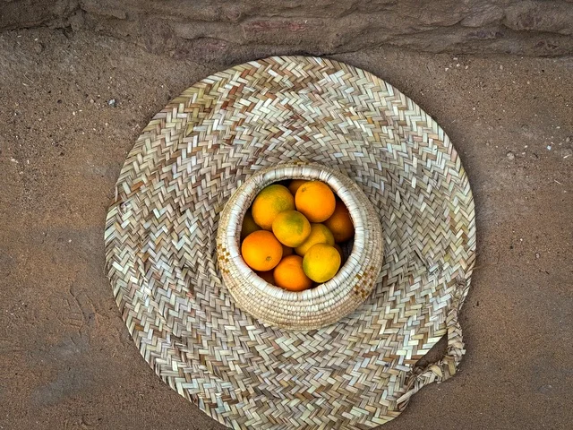 مجموعة من حبات البرتقال الطازج في سلة تقليدية مصنوعة من القش، المزارع والواحات الخصبة في البلدة القديمة بالعلا، منتجات وطنية محلية، المناظر الطبيعية المتميزة في المملكة العربية السعودية، محمية طبيعية لزراعة الاشجار