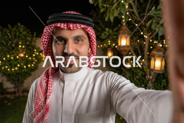 شهر رمضان المبارك، رجل عربي خليجي سعودي يرتدي الزي التقليدي والشماغ  يلتقط صورة سيلفي تذكارية ، إضاءة وزينة شهر رمضان، أجواء رمضانية، مناسبات دينية ، اسلاميات وعبادات