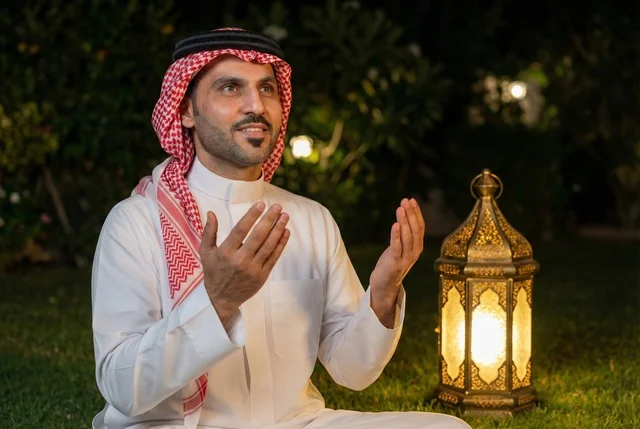 Remembrances, supplications, and obligations, bowing, prostration, and humility before God. An Arab Saudi Gulf man wearing traditional attire and a headscarf sits on the prayer rug and performs the obligatory prayer, performing the Taraweeh prayer during the holy month of Ramadan, supplicating and beseeching God.