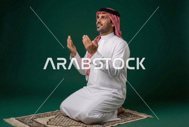 أذكار وأدعية وفرائض، الركوع والسجود والخشوع لله، رجل عربي سعودي خليجي يرتدي الثوب التقليدي والشماغ يجلس على السجادة و يؤدي فريضة الصلاة ، آداء صلاة التراويح فى شهر رمضان الكريم ، الدعاء والتضرع الى الله