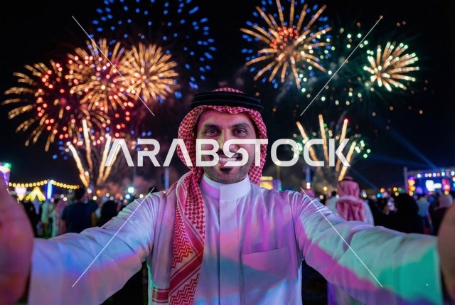 أجواء الاحتفالات السنوية في المملكة, الفعاليات الاحتفالية الترفيهية بالأعياد والمناسبات, الاستعداد لقدوم العام الجديد, انطلاق المفرقعات والألعاب النارية في سماء السعودية ليلا, رجل عربي خليجي سعودي يرتدي الزى التقليدي والشماغ يحتفل بعيد رأس السنة الميلادية 2026