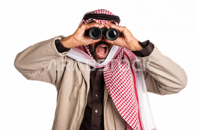 بورتريه لرجل عربي خليجي سعودي يرتدي ملابس الشتاء الدافئة، النظر من خلال الناظور، إيماءات وجه تدل على الدهشة والتعجب، ملابس لتدفئة الجسم، الاستكشاف والمغامرة، فريق الكشافة، رؤية مستقبلية، التخطيط المستقبلي، اهداف وطموحات، اجواء شتوية، خلفية بيضاء