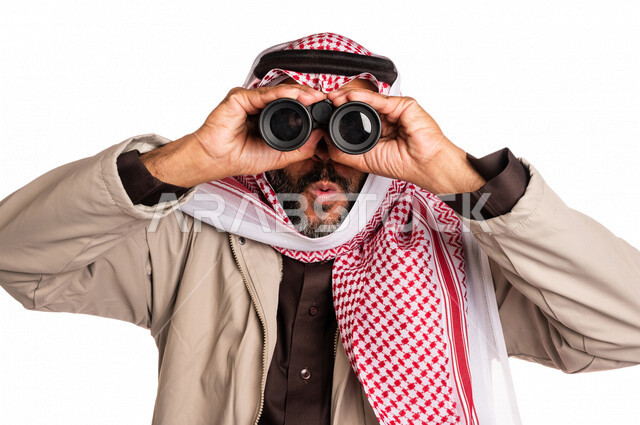 بورتريه لرجل عربي خليجي سعودي يرتدي ملابس الشتاء الدافئة، النظر من خلال الناظور، إيماءات وجه تدل على الدهشة والتعجب، ملابس لتدفئة الجسم، الاستكشاف والمغامرة، فريق الكشافة، رؤية مستقبلية، التخطيط المستقبلي، اهداف وطموحات، اجواء شتوية، خلفية بيضاء