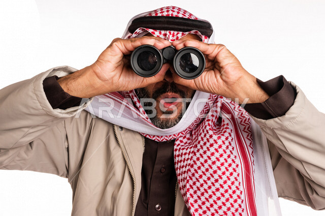 بورتريه لرجل عربي خليجي سعودي يرتدي ملابس الشتاء الدافئة، النظر من خلال الناظور، إيماءات وجه تدل على الدهشة والتعجب، ملابس لتدفئة الجسم، الاستكشاف والمغامرة، فريق الكشافة، رؤية مستقبلية، التخطيط المستقبلي، اهداف وطموحات، اجواء شتوية، خلفية بيضاء