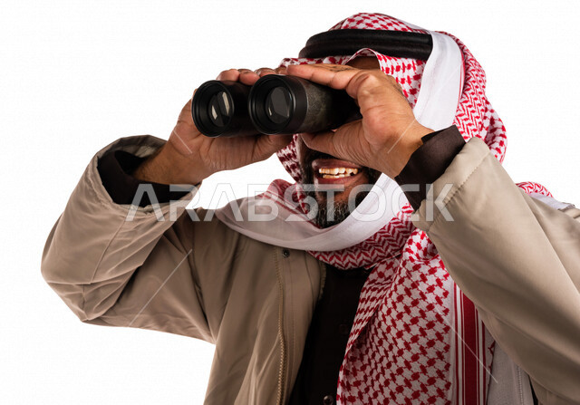 بورتريه لرجل عربي خليجي سعودي يرتدي ملابس الشتاء الدافئة، النظر من خلال الناظور، إيماءات وجه تدل على الدهشة والتعجب، ملابس لتدفئة الجسم، الاستكشاف والمغامرة، فريق الكشافة، رؤية مستقبلية، التخطيط المستقبلي، اهداف وطموحات، اجواء شتوية، خلفية بيضاء