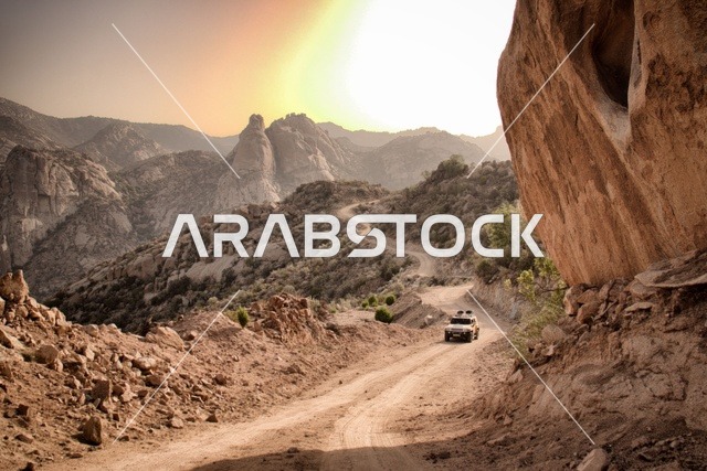 The archaeological buildings in the old town of Al-Ula in the Kingdom of Saudi Arabia, the peaks and mountainous elevations, the ancient historical landmarks and areas, an asphalt road paved between the houses and the traditional mud houses, the rock formations and structures in the tourist areas.