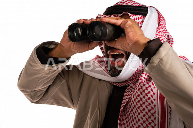 بورتريه لرجل عربي خليجي سعودي يرتدي ملابس الشتاء الدافئة، النظر من خلال الناظور، إيماءات وجه تدل على الدهشة والتعجب، ملابس لتدفئة الجسم، الاستكشاف والمغامرة، فريق الكشافة، رؤية مستقبلية، التخطيط المستقبلي، اهداف وطموحات، اجواء شتوية، خلفية بيضاء