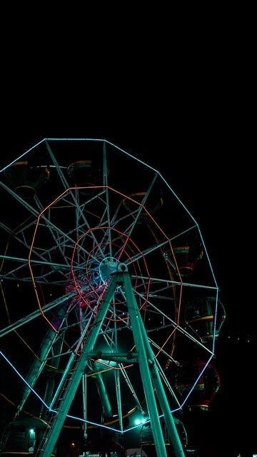 قضاء اوقات  المرح والتسلية في مدينة الألعاب في وضع الليل ،لعبة العجلة الدوارة في مدينة الملاهي ، التسلية والترفيه ، العطلة الصيفية ، عطلة نهاية الأسبوع