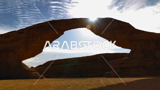 The famous Arch Rock in the desert areas of the Kingdom of Saudi Arabia, ancient historical archaeological sites, famous natural tourist attractions, rock formations and structures in the desert of Al-Ula Governorate, peaks and mountain elevations amidst the sandy environment.