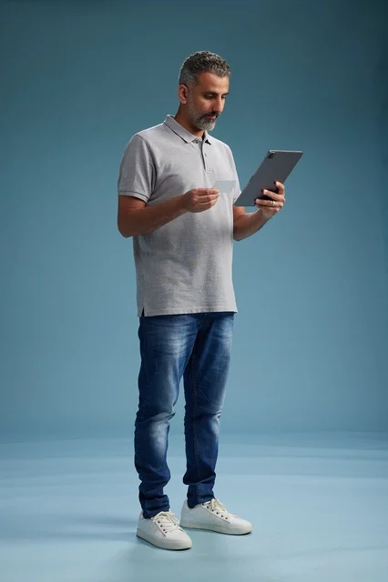 رجل عربي سعودي خليجي يرتدي الزي الكاجوال يمسك بيده جهاز لوحي, ايماءات وحركات متنوعه, الجسم بالطول, الكامل خلفيه زرقاء