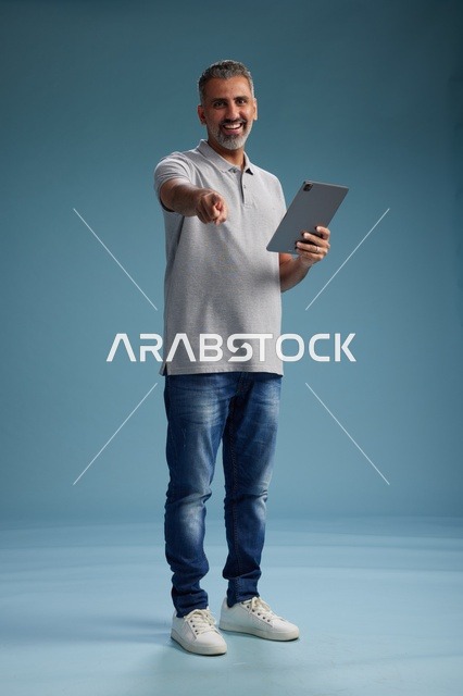 رجل عربي سعودي خليجي يرتدي الزي الكاجوال يمسك بيده جهاز لوحي, ايماءات وحركات متنوعه, الجسم بالطول, الكامل خلفيه زرقاء