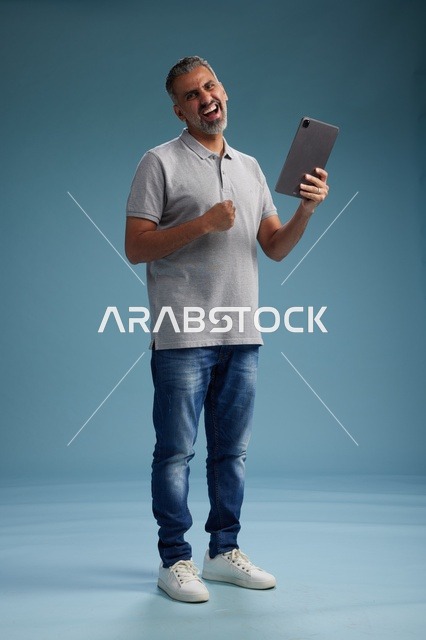 رجل عربي سعودي خليجي يرتدي الزي الكاجوال يمسك بيده جهاز لوحي, ايماءات وحركات متنوعه, الجسم بالطول, الكامل خلفيه زرقاء