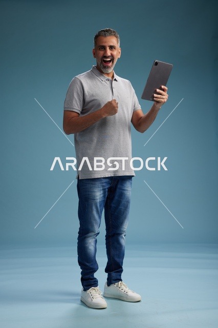 رجل عربي سعودي خليجي يرتدي الزي الكاجوال يمسك بيده جهاز لوحي, ايماءات وحركات متنوعه, الجسم بالطول, الكامل خلفيه زرقاء