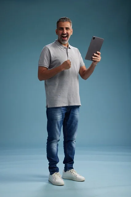 رجل عربي سعودي خليجي يرتدي الزي الكاجوال يمسك بيده جهاز لوحي, ايماءات وحركات متنوعه, الجسم بالطول, الكامل خلفيه زرقاء