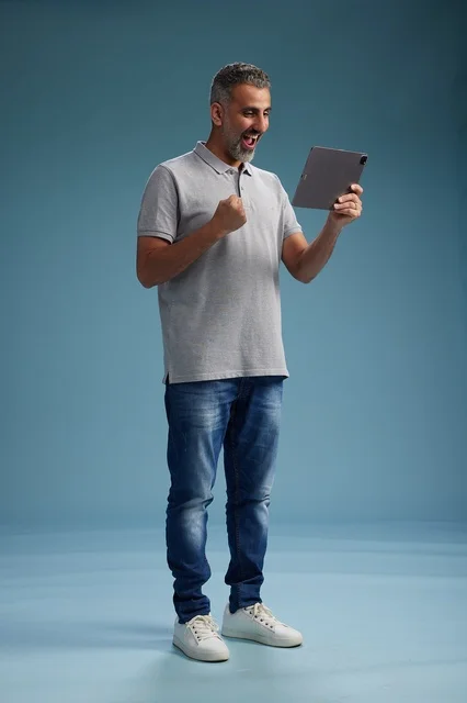 رجل عربي سعودي خليجي يرتدي الزي الكاجوال يمسك بيده جهاز لوحي, ايماءات وحركات متنوعه, الجسم بالطول, الكامل خلفيه زرقاء