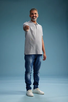 A Saudi Arabian Gulf Arab man wearing casual attire holding a blank white card, full body, blue background.