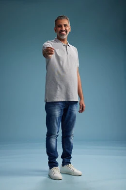 A Saudi Arabian Gulf Arab man wearing casual attire holding a blank white card, full body, blue background.