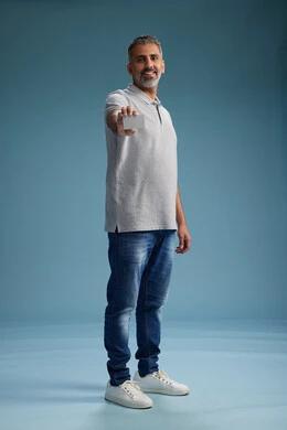 A Saudi Arabian Gulf Arab man wearing casual attire holding a blank white card, full body, blue background.