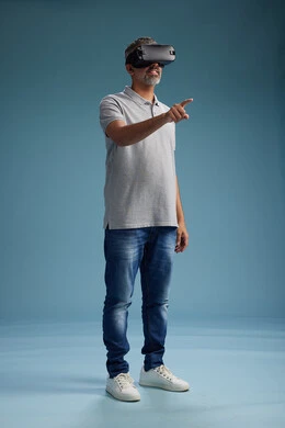 رجل عربي سعودي خليجي يرتدي الزي الكاجوال يستخدم نظارة الواقع الافتراضي, مشاهدة الافلام والفيديوز المسليه عبر الفي ار, كامل الجسم, خلفيه زرقاء