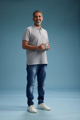 A Saudi Arabian Gulf Arab man enjoying a cup of coffee in casual clothes, full body, blue background. A Saudi Arabian Gulf Arab man enjoying a cup of coffee in casual clothes, full body, blue background.