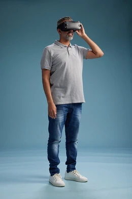 رجل عربي سعودي خليجي يرتدي الزي الكاجوال يستخدم نظارة الواقع الافتراضي, مشاهدة الافلام والفيديوز المسليه عبر الفي ار, كامل الجسم, خلفيه زرقاء