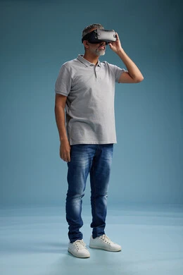 رجل عربي سعودي خليجي يرتدي الزي الكاجوال يستخدم نظارة الواقع الافتراضي, مشاهدة الافلام والفيديوز المسليه عبر الفي ار, كامل الجسم, خلفيه زرقاء