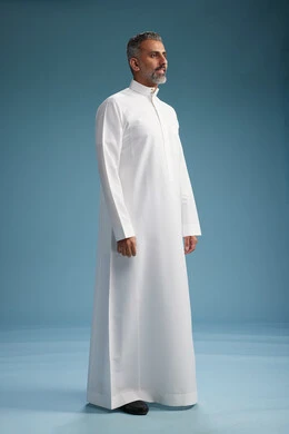 رجل عربي  سعودي خليجي يرتدي ثوب ابيض  , النظر الى شيء ما, الوقوف بثقه, كامل الجسم, خلفيه زرقاء