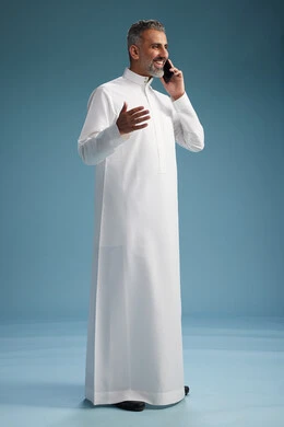 رجل عربي سعودي خليجي يرتدي الثوب الابيض يجري مكالمة هاتفية بايماءات وحركات متنوعه, التواصل مع الاصدقاء عبر الجوال, كامل الجسم, خلفيه زرقاء رجل عربي سعودي خليجي يرتدي الثوب الابيض يجري مكالمة هاتفية بايماءات وحركات متنوعه, التواصل مع الاصدقاء عبر الجوال, كامل الجسم, خلفيه زرقاء