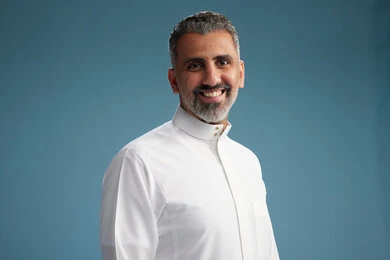 صورة مقربه لرجل عربي  سعودي خليجي يرتدي ثوب ابيض  , النظر الى الكاميرا, الوقوف بثقه, خلفيه زرقاء